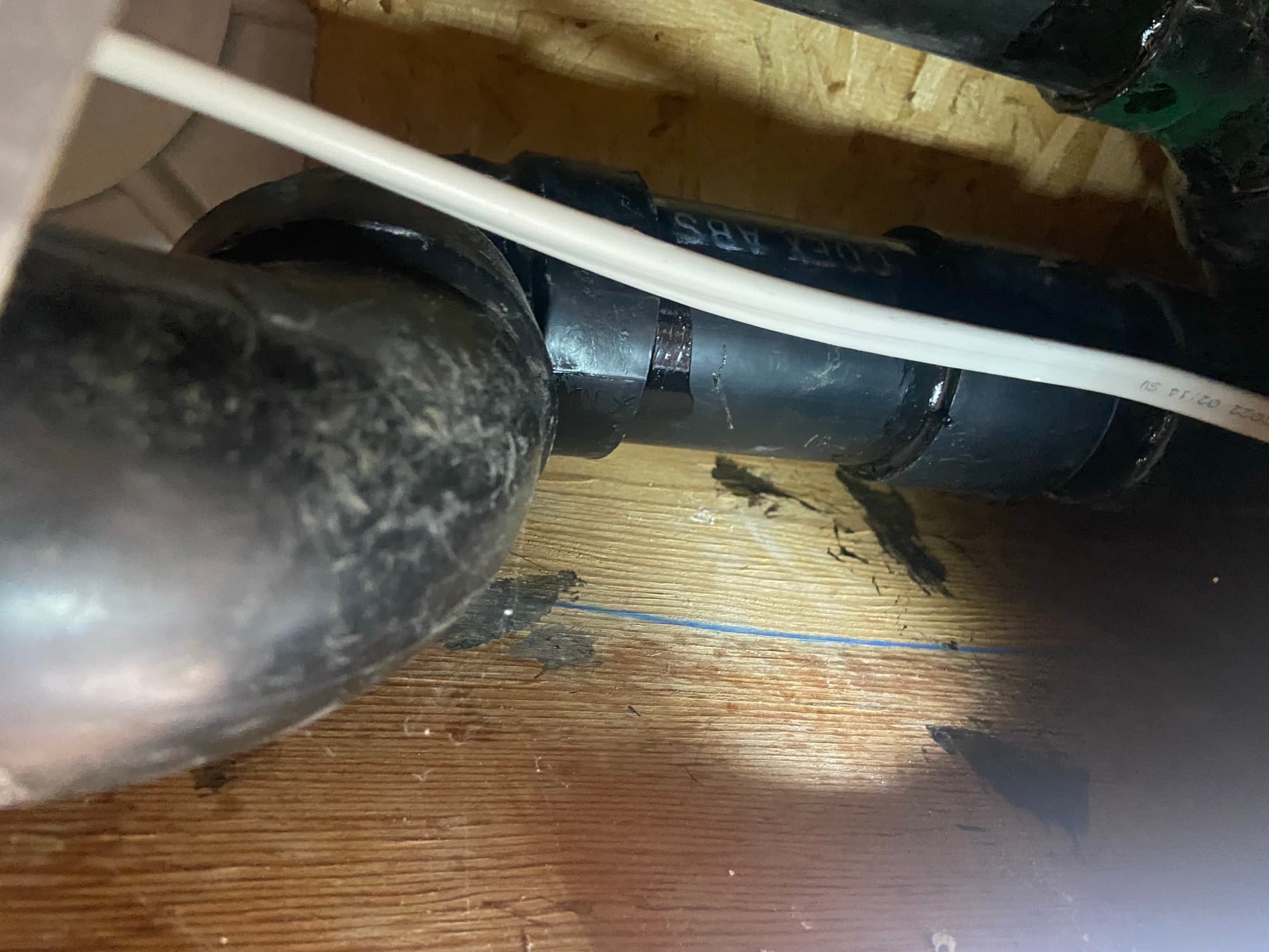 ABS drain pipe joint running near a PEX supply line beneath floor joists, Orange County, CA