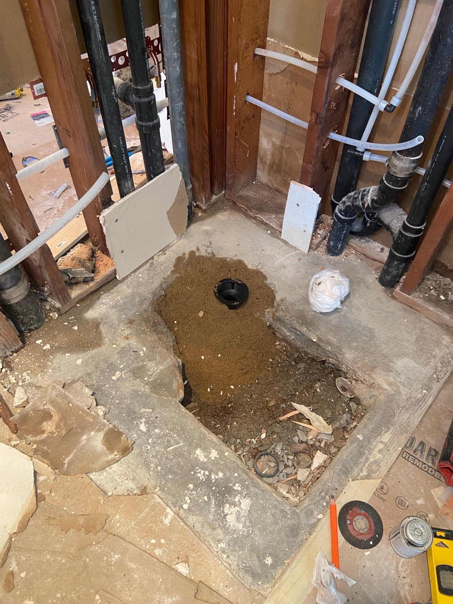 Black ABS pipe fitting set in sand within a floor excavation, Orange County, CA