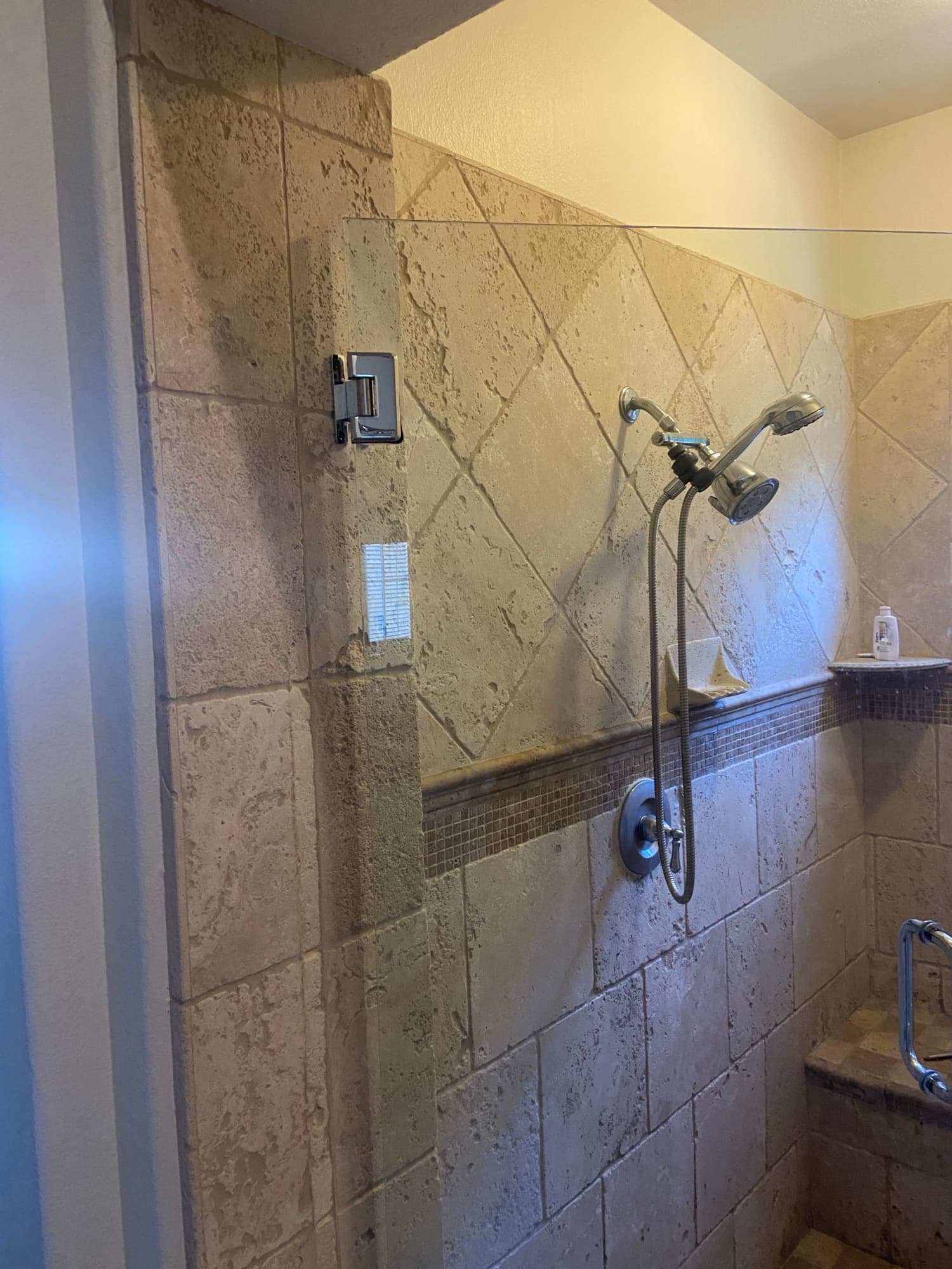 Travertine tile shower fitted with a low-mounted handheld sprayer for accessible bathing, Orange County, CA