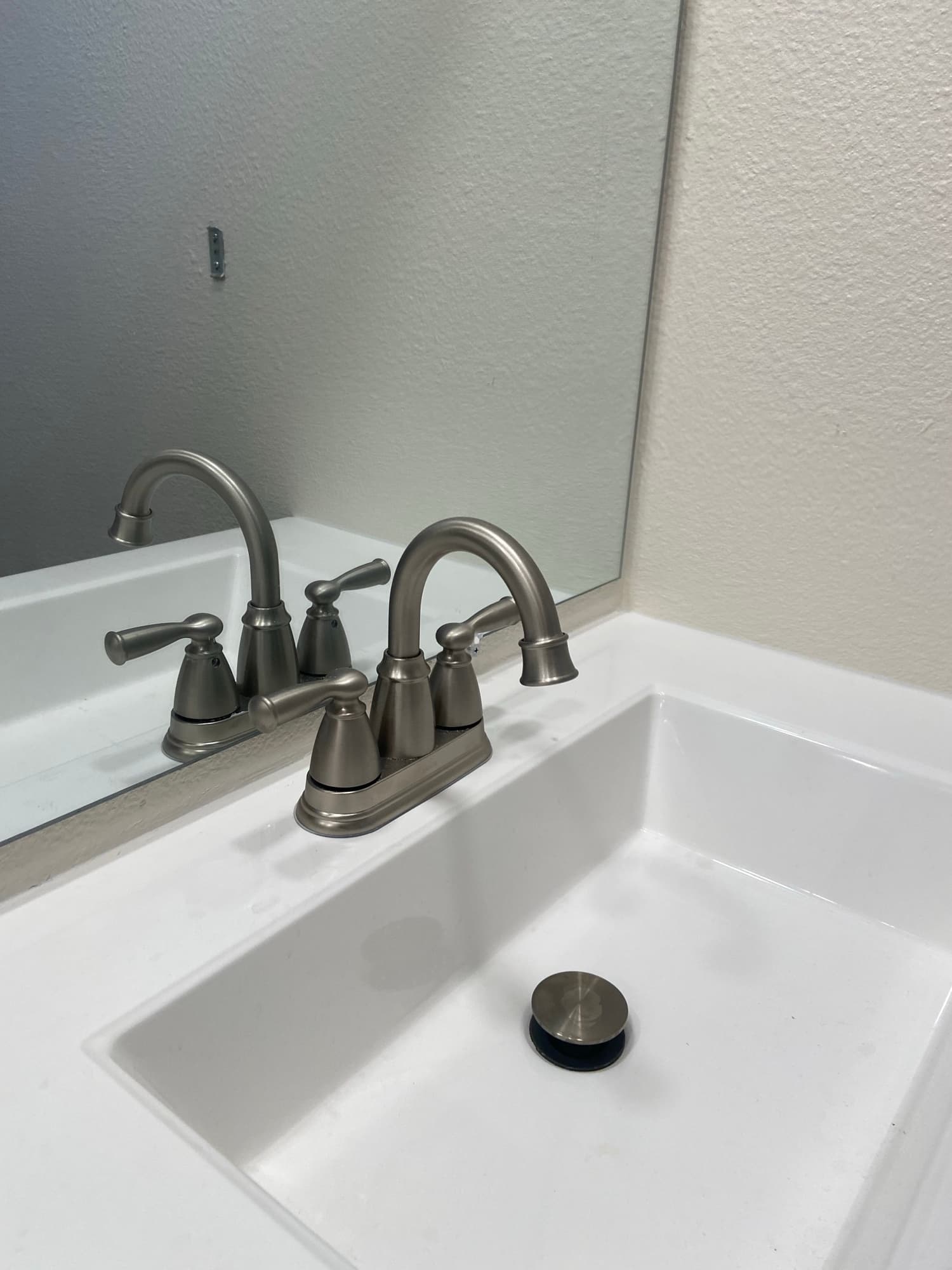 Newly installed brushed nickel faucet above a white bathroom sink, Orange County, CA
