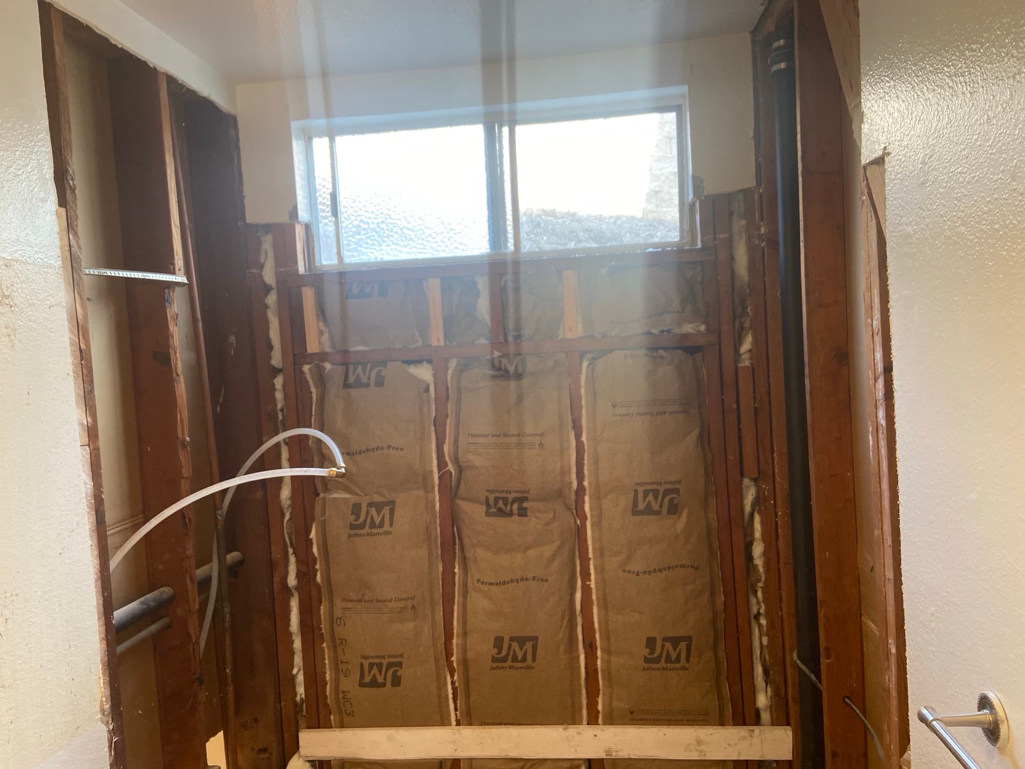 Bathroom wall opened to the studs showing new insulation and plumbing rough-in, Orange County, CA