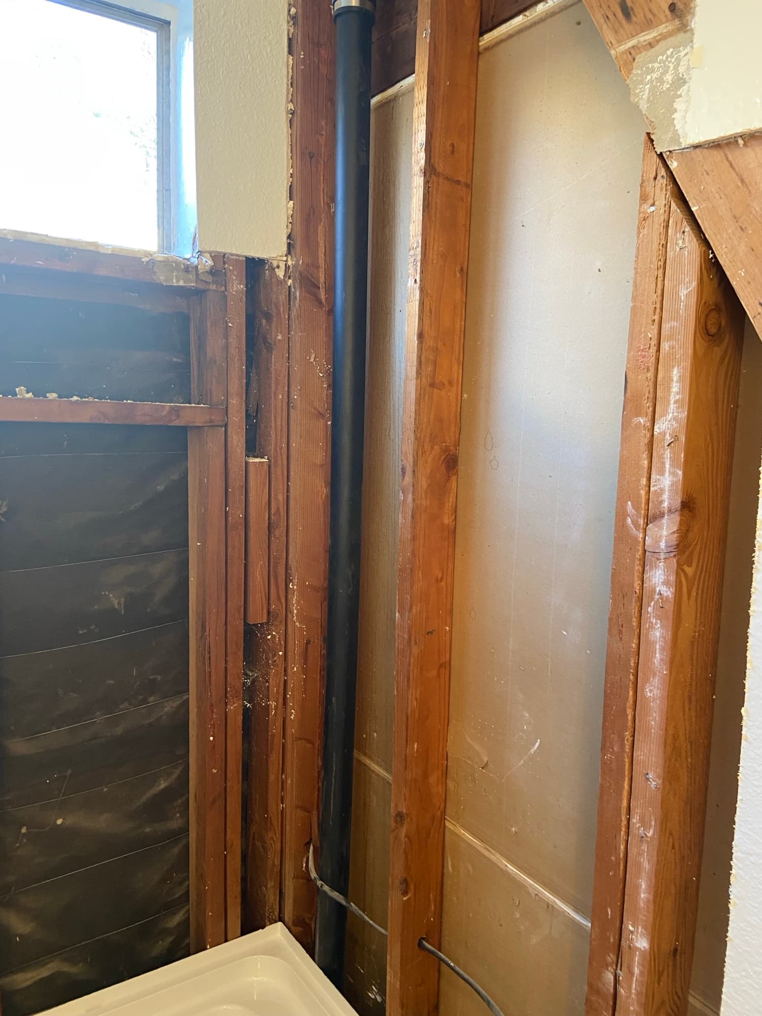 Drain vent pipe visible in open ceiling framing during a bathroom remodel, Orange County, CA