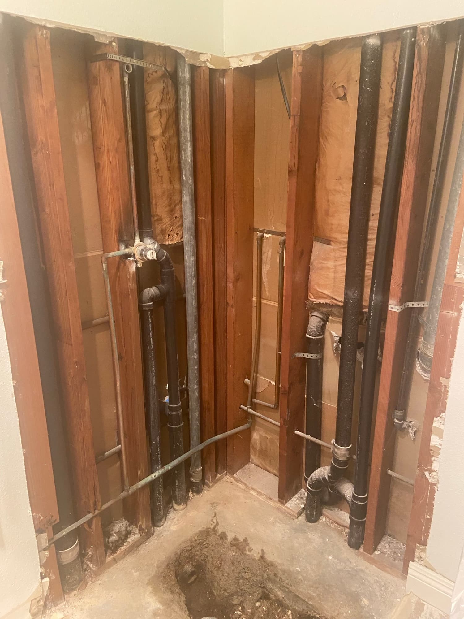 Overhead view of ABS drain lines and copper water pipes running through floor joists, Orange County
