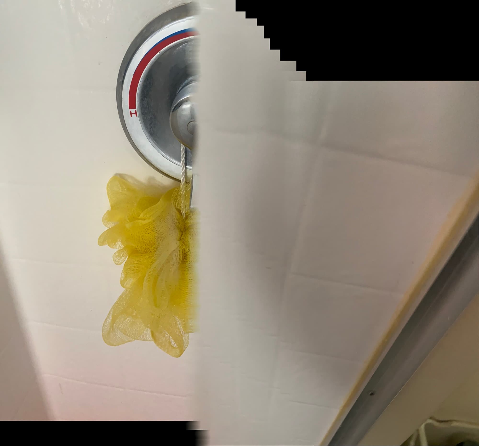 Close-up of a shower valve handle and hanging loofah in an Orange County bathroom