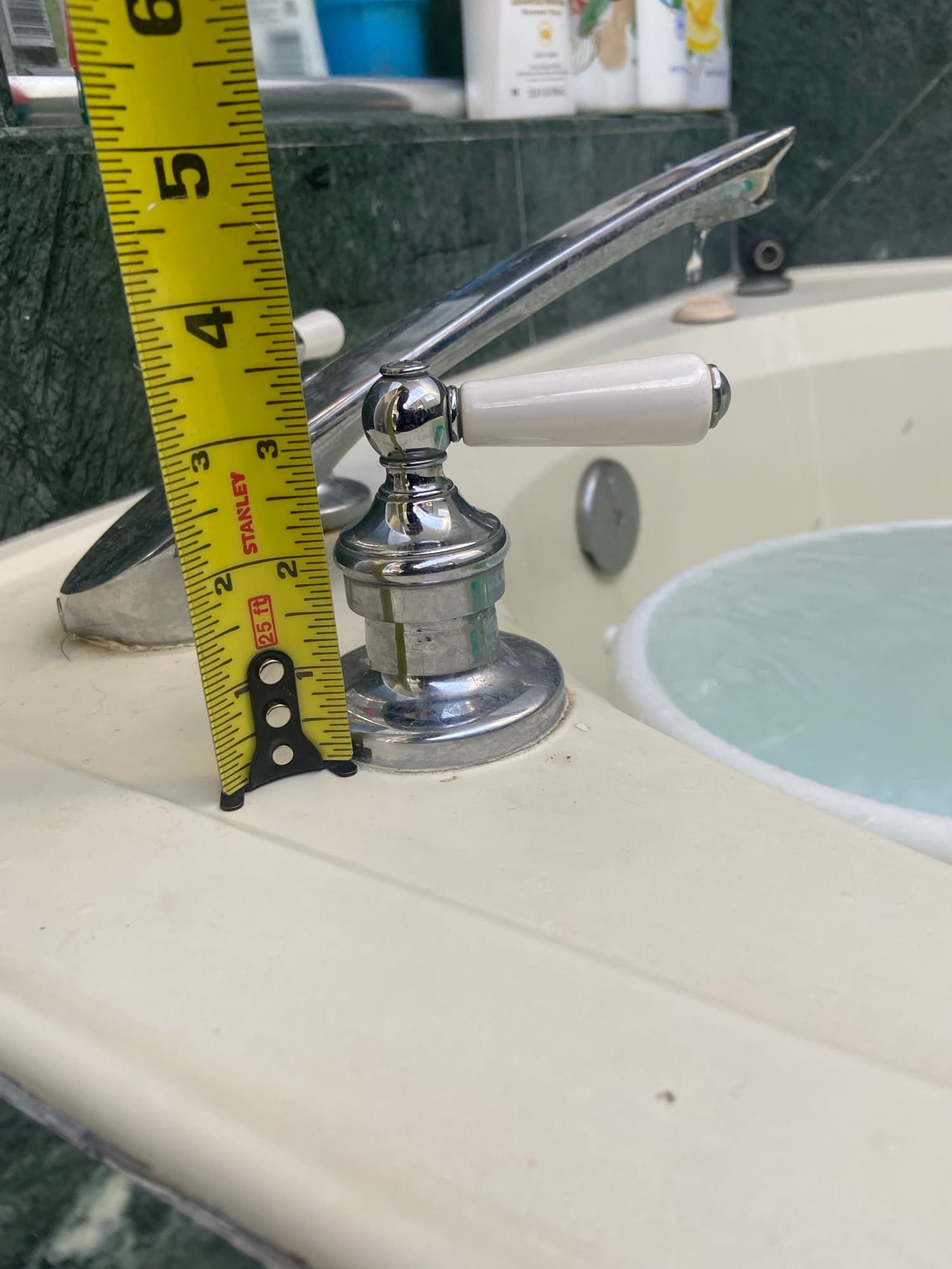 Technician measuring clearance above a chrome tub faucet while the tub fills, Orange County, CA