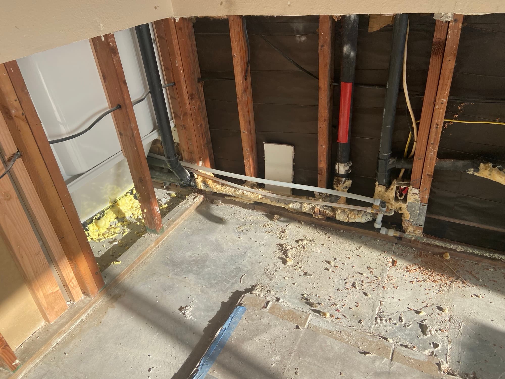 Open wall framing reveals a black vent pipe near a bathtub, Orange County, CA