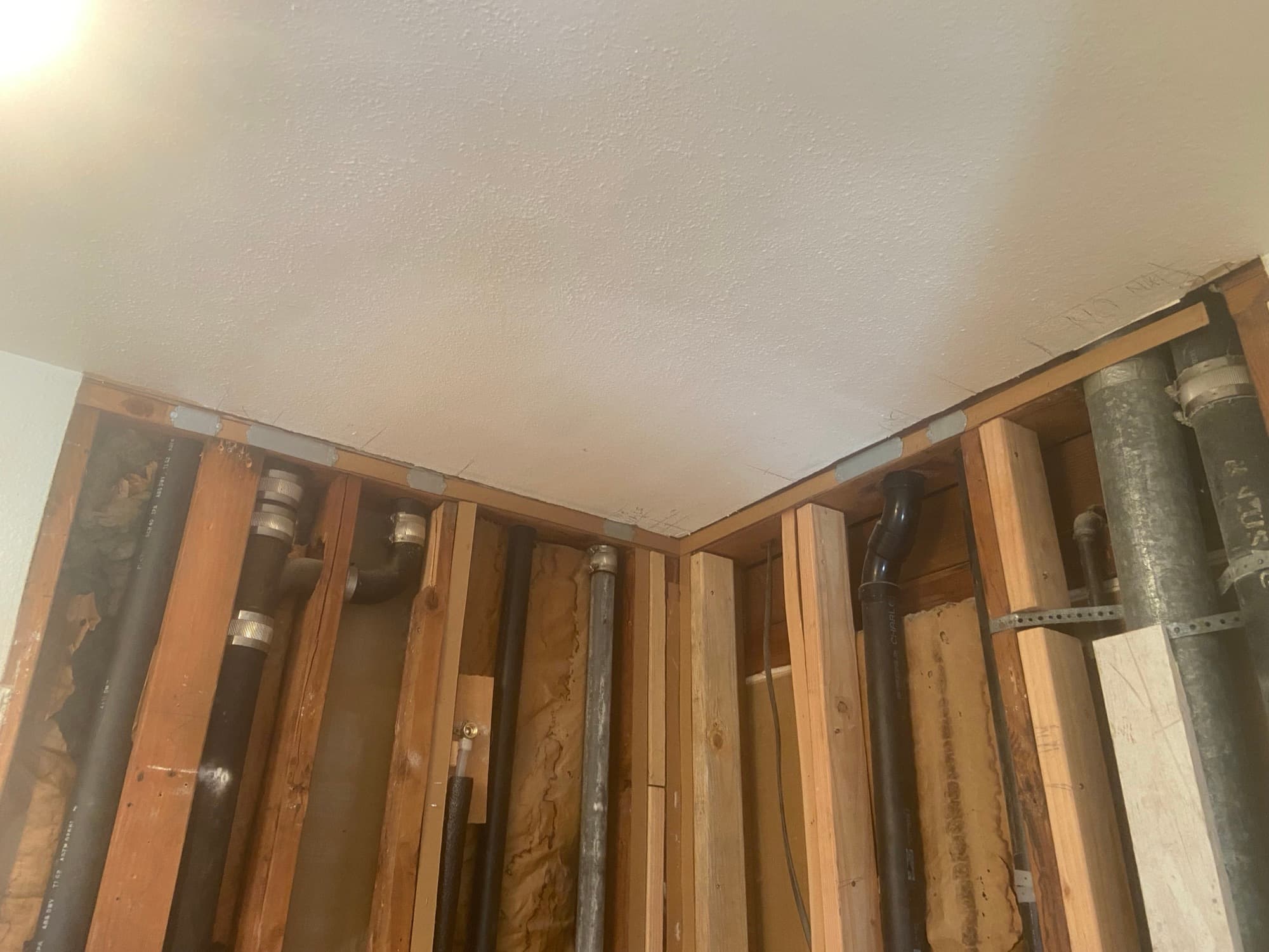 Corner of ceiling framing with multiple vertical drain and vent pipe stub-outs, Orange County, CA